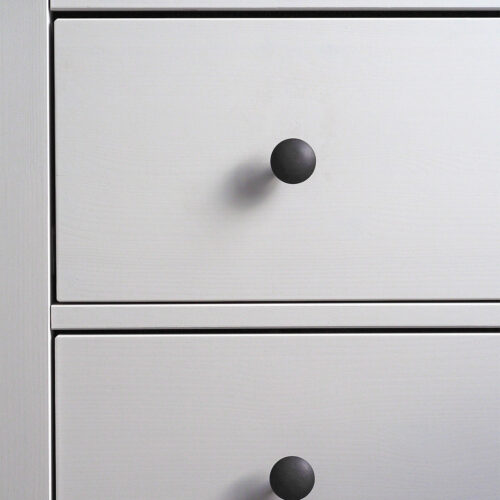 close-up of a modern white wooden chest of drawers with black handles. Minimalism,
